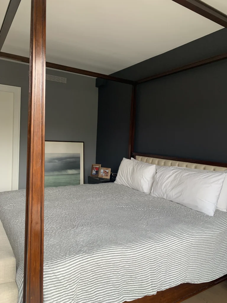 a love seat in front of a 4 post wood bed
